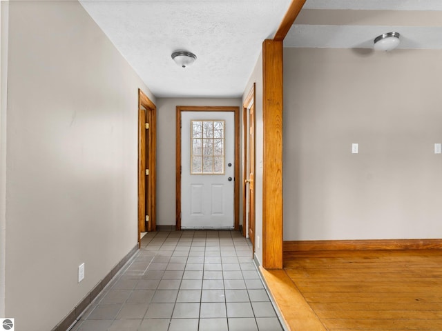 interior space with a textured ceiling, baseboards, and light tile patterned floors