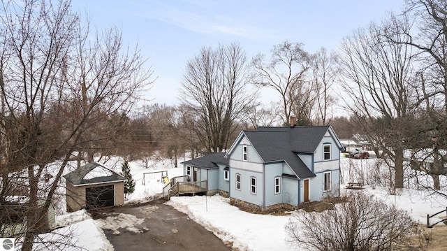 view of front of property with a garage, driveway, roof with shingles, and an outdoor structure