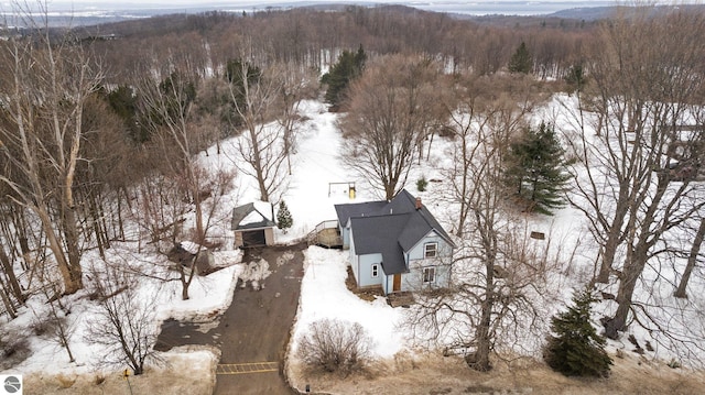 snowy aerial view featuring a wooded view