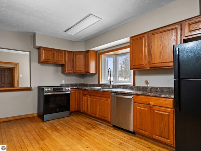 kitchen with dark countertops, brown cabinetry, stainless steel appliances, and a sink