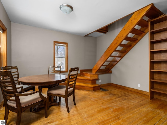 dining space with baseboards, stairway, and light wood-style floors