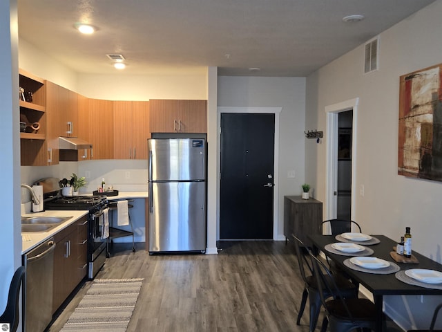 kitchen with stainless steel appliances, light countertops, visible vents, wood finished floors, and under cabinet range hood