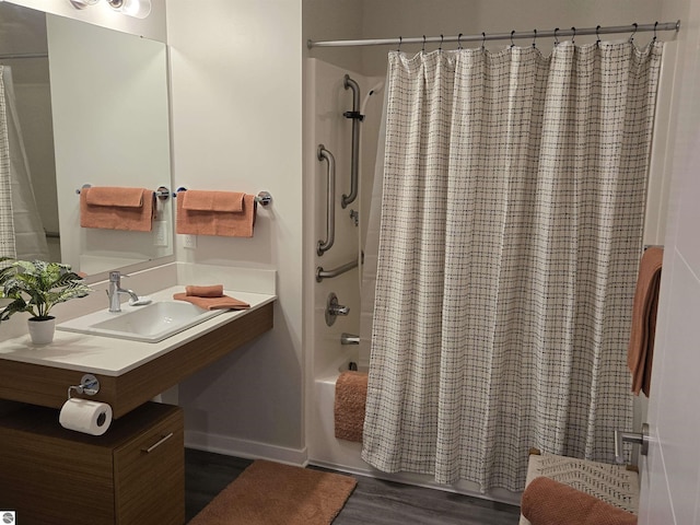 full bath featuring shower / bath combo, a sink, and wood finished floors