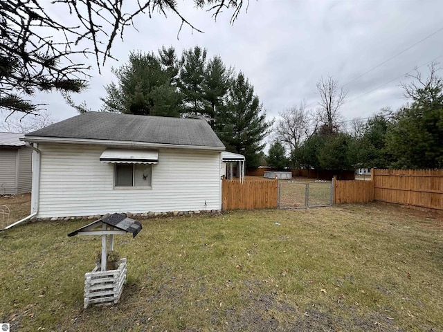 rear view of property featuring a yard, a gate, and fence