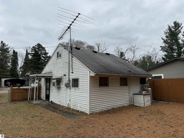 view of side of property featuring a shingled roof, fence, and a lawn