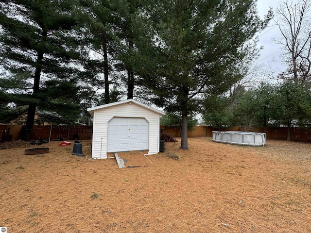 detached garage with fence and a fenced in pool