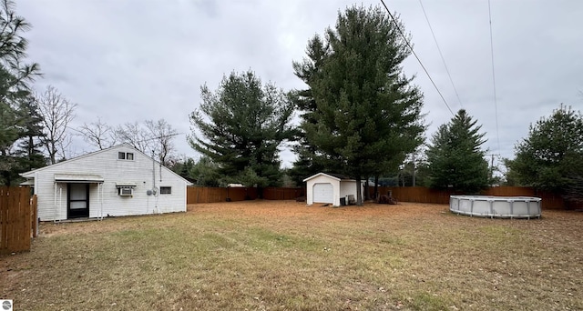 view of yard with a fenced in pool, a fenced backyard, an outdoor structure, and a storage shed