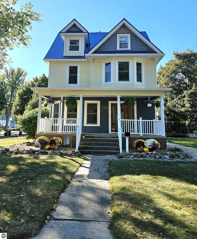 view of front facade featuring covered porch, metal roof, and a front yard