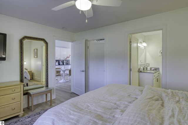 bedroom featuring ceiling fan, connected bathroom, a sink, and wood finished floors