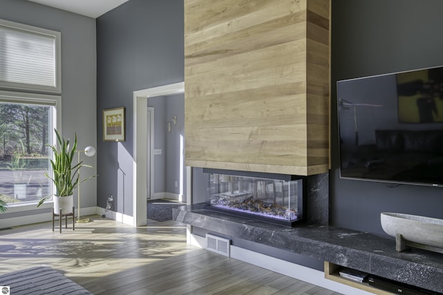 living room with wood-type flooring, a fireplace, visible vents, and baseboards