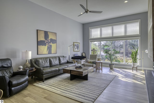 living room featuring recessed lighting, wood-type flooring, ceiling fan, and a high ceiling