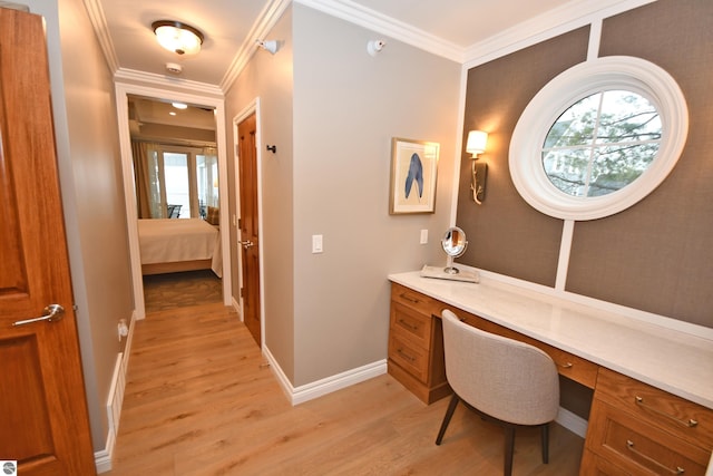 office space featuring ornamental molding, light wood-type flooring, built in desk, and baseboards