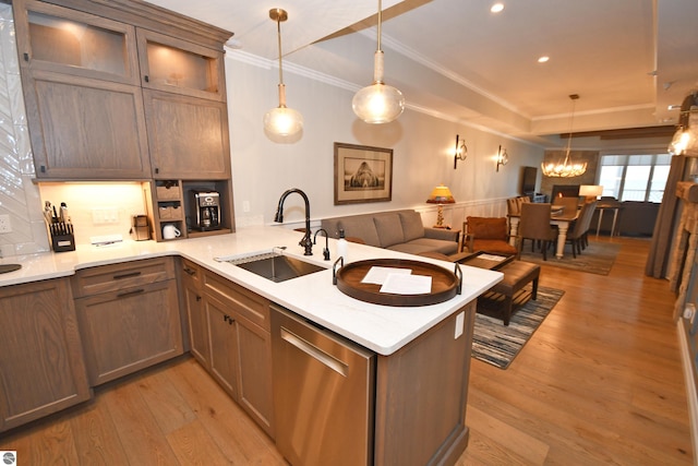 kitchen with light wood-style flooring, a peninsula, a sink, pendant lighting, and stainless steel dishwasher