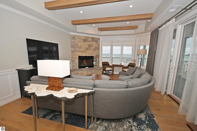 living area featuring a decorative wall, beam ceiling, and wood finished floors