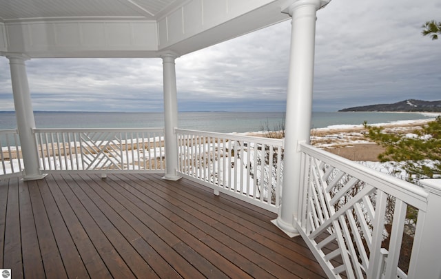 wooden deck featuring a water view and a beach view