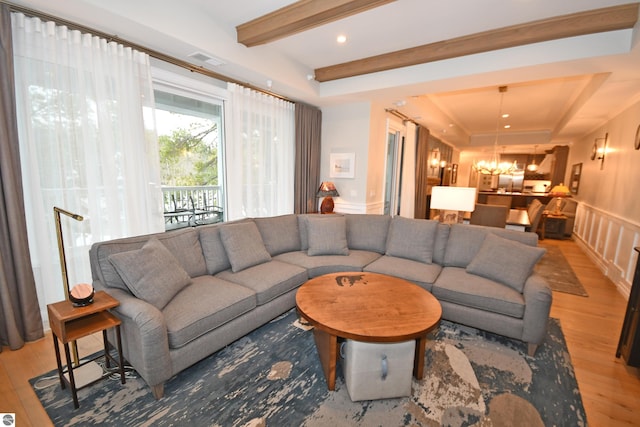 living room with visible vents, a tray ceiling, light wood-style floors, a decorative wall, and beam ceiling