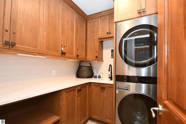 clothes washing area with stacked washing maching and dryer and cabinet space