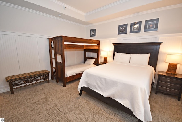 bedroom featuring carpet floors, a raised ceiling, a wainscoted wall, and crown molding