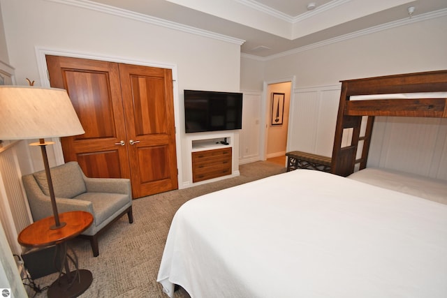 carpeted bedroom with a wainscoted wall, a tray ceiling, a decorative wall, and crown molding