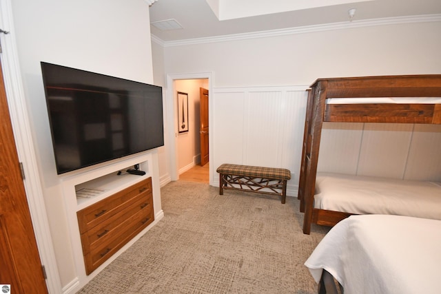 bedroom with ornamental molding, wainscoting, and light colored carpet