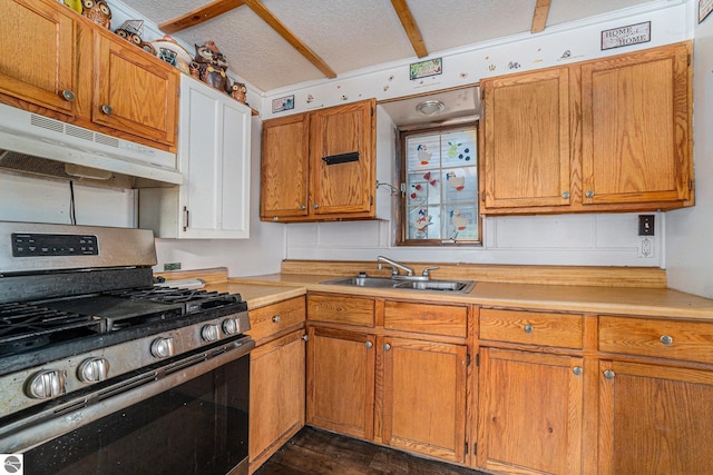 kitchen with a textured ceiling, under cabinet range hood, a sink, light countertops, and stainless steel gas stove