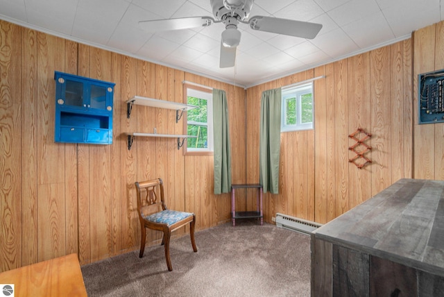 sitting room featuring a baseboard heating unit, ceiling fan, carpet flooring, and wooden walls