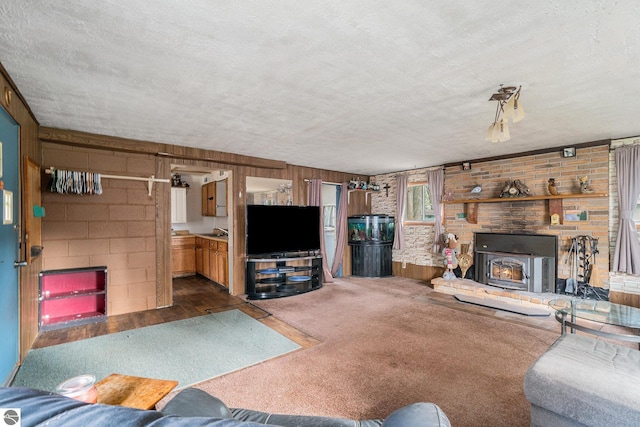 living area with carpet floors, a fireplace, a textured ceiling, and concrete block wall