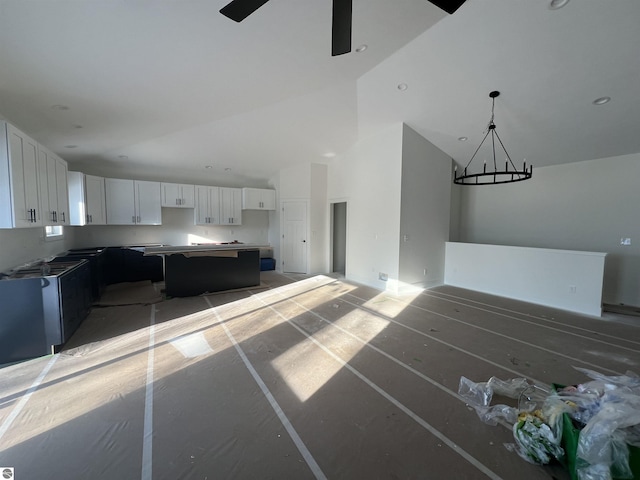 kitchen featuring a kitchen island, open floor plan, white cabinetry, high vaulted ceiling, and ceiling fan with notable chandelier