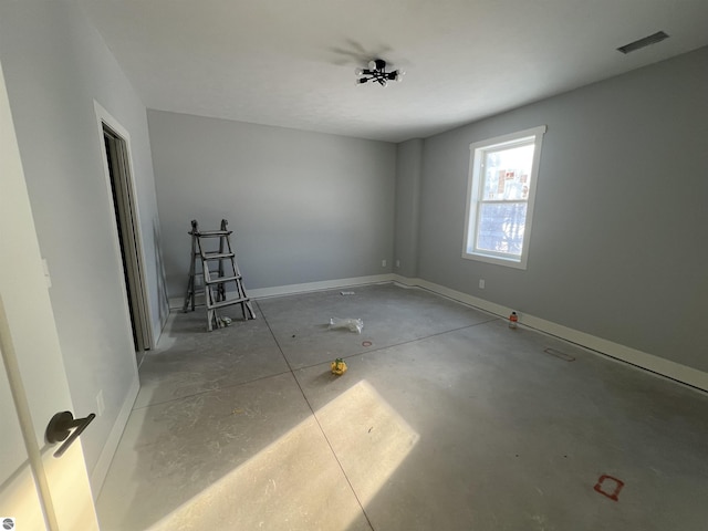 empty room featuring concrete floors, visible vents, and baseboards