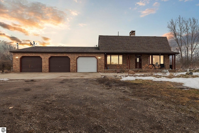 view of front of property with brick siding, roof with shingles, a chimney, concrete driveway, and a garage