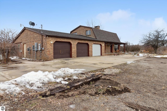 view of home's exterior with brick siding, a chimney, a shingled roof, concrete driveway, and an attached garage