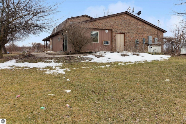 view of snowy exterior with brick siding and a lawn