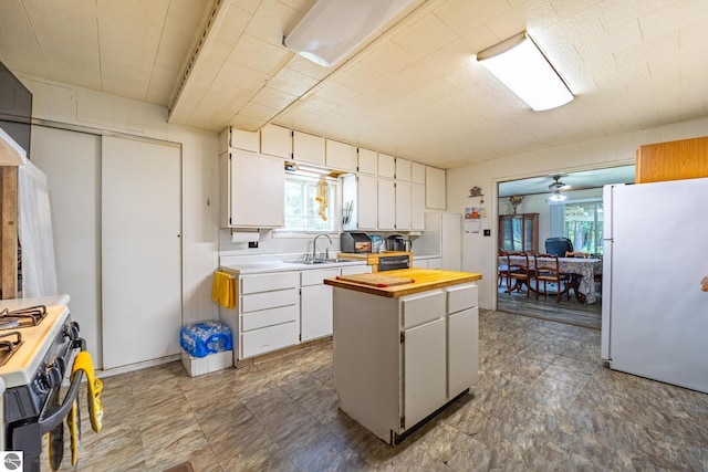 kitchen with range with gas cooktop, wooden counters, a sink, and freestanding refrigerator