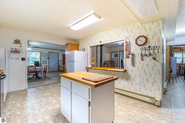 kitchen featuring wallpapered walls, wood counters, freestanding refrigerator, a baseboard heating unit, and gas water heater