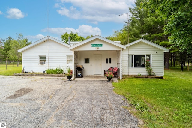 view of front of property featuring a front lawn, cooling unit, and aphalt driveway