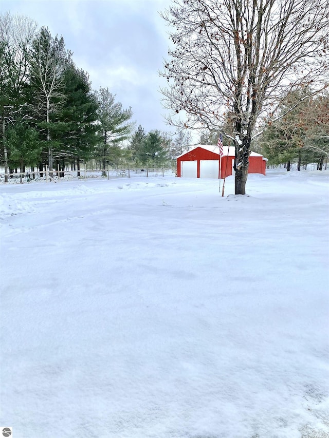 yard covered in snow with a detached garage, a pole building, and an outdoor structure