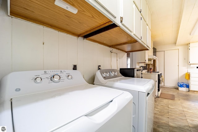 clothes washing area featuring washer and dryer and cabinet space