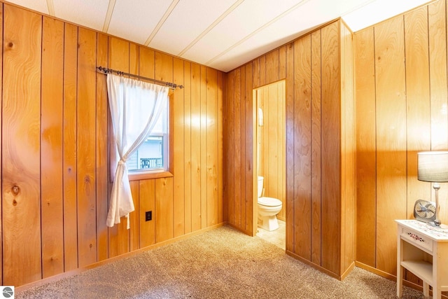 bedroom featuring ensuite bathroom, carpet flooring, and wooden walls