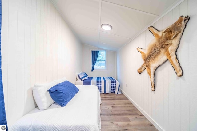 bedroom featuring lofted ceiling, wood finished floors, and baseboards