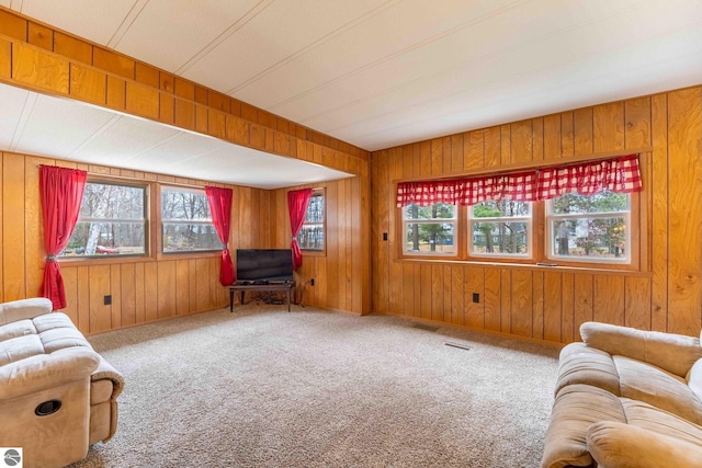 carpeted living area featuring wooden walls