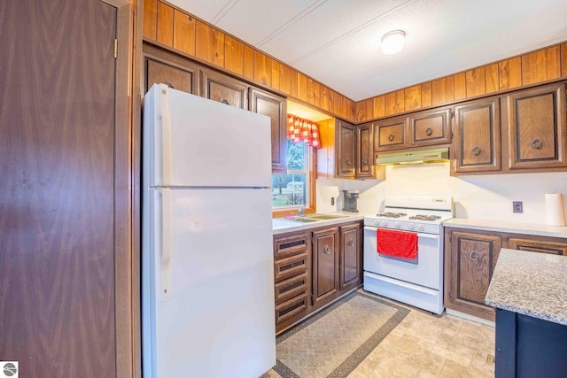 kitchen with brown cabinets, white appliances, light countertops, and under cabinet range hood