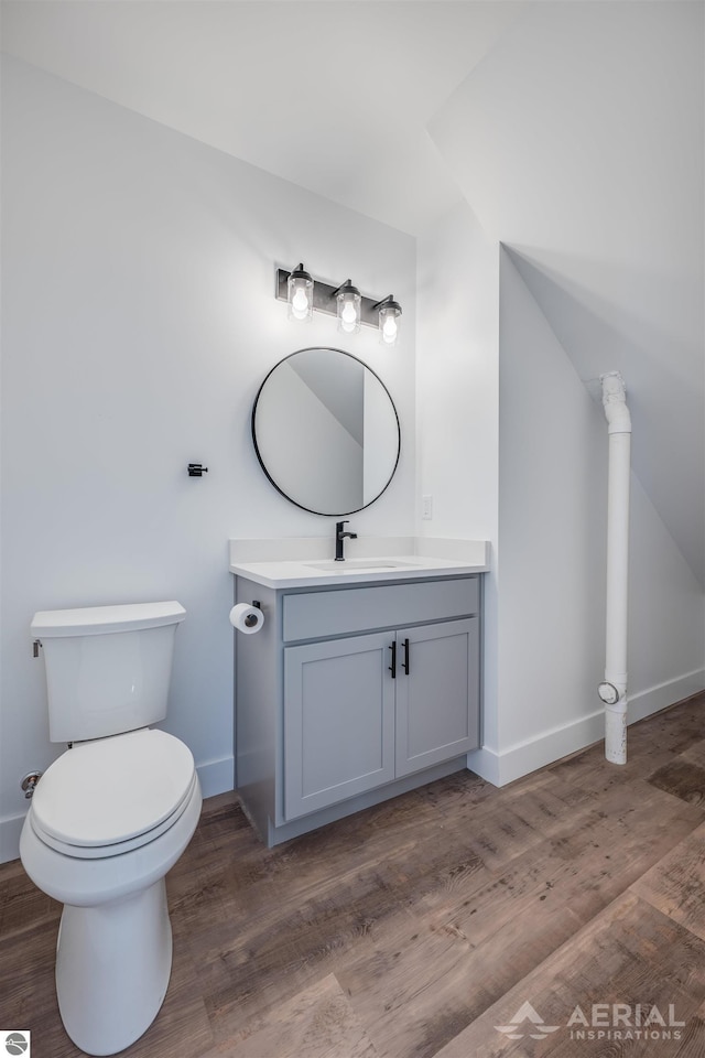 half bathroom featuring baseboards, vanity, toilet, and wood finished floors