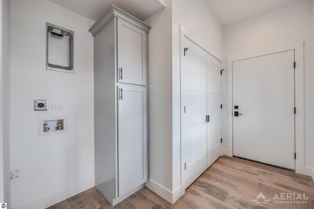 interior space featuring hookup for a washing machine, baseboards, hookup for an electric dryer, and light wood finished floors