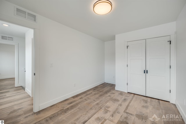 unfurnished bedroom featuring a closet, baseboards, visible vents, and light wood finished floors