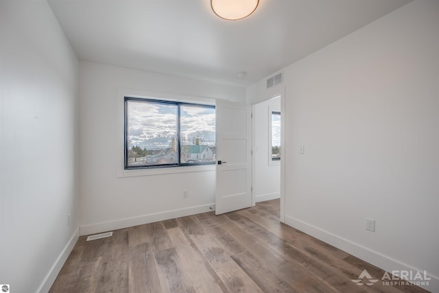 empty room with baseboards, visible vents, and wood finished floors