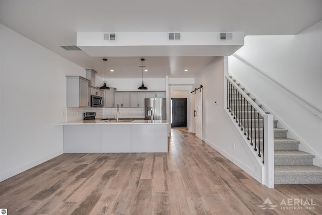 kitchen featuring stainless steel appliances, visible vents, and a barn door