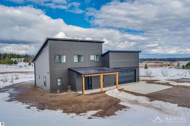 view of front of house featuring driveway, a garage, metal roof, a standing seam roof, and board and batten siding