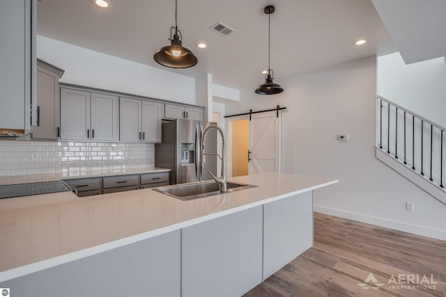 kitchen with a barn door, backsplash, a sink, and gray cabinetry