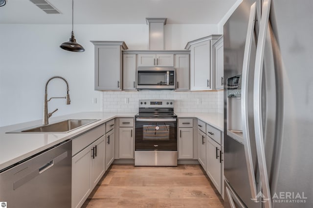 kitchen featuring visible vents, gray cabinetry, appliances with stainless steel finishes, a sink, and light wood-type flooring