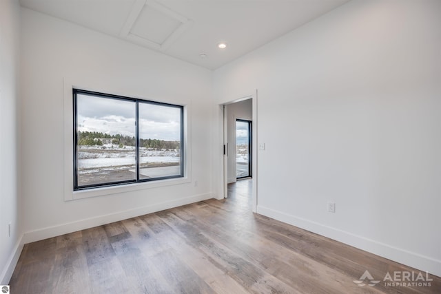 spare room with attic access, baseboards, wood finished floors, and recessed lighting